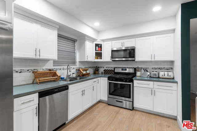 kitchen with white cabinetry, stainless steel appliances, sink, and light hardwood / wood-style flooring