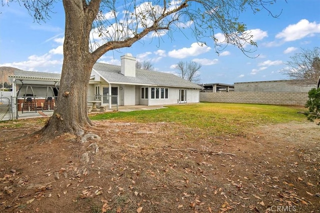 rear view of property featuring a yard and a patio area