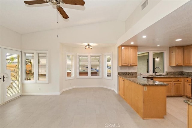 kitchen featuring dark stone countertops, sink, vaulted ceiling, and kitchen peninsula