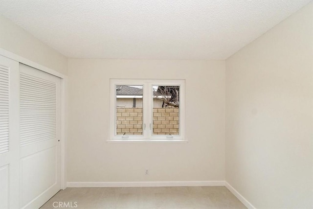 unfurnished bedroom featuring light carpet, a textured ceiling, and a closet