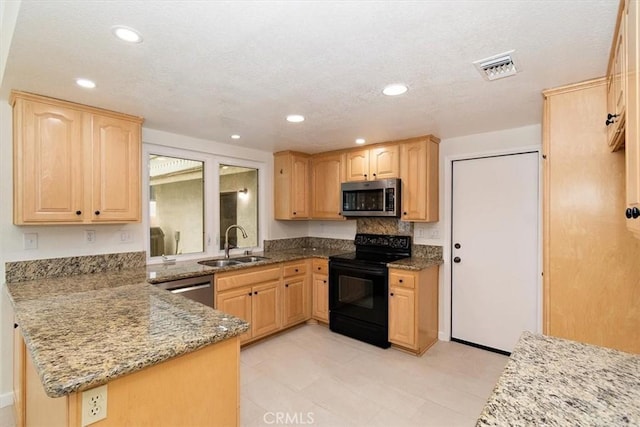 kitchen featuring appliances with stainless steel finishes, light brown cabinetry, sink, and stone counters