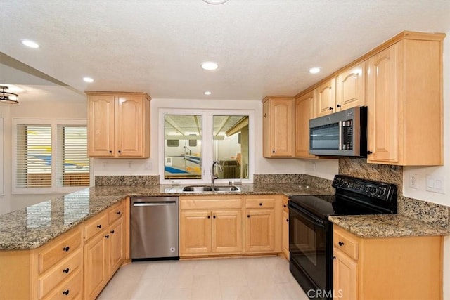 kitchen with light brown cabinetry, sink, dark stone countertops, kitchen peninsula, and stainless steel appliances