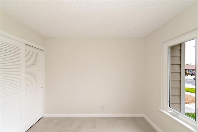 unfurnished bedroom featuring a closet, multiple windows, and a textured ceiling