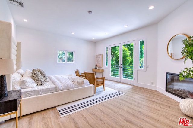 bedroom with access to exterior, light wood-type flooring, and french doors