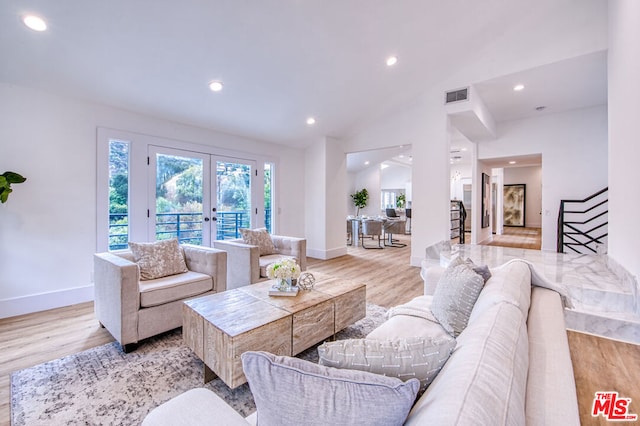 living room featuring french doors, lofted ceiling, and light hardwood / wood-style floors