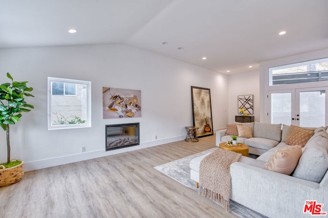 living room with vaulted ceiling, light hardwood / wood-style floors, and french doors