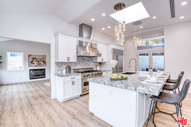 kitchen with hanging light fixtures, light stone counters, white cabinets, and premium appliances