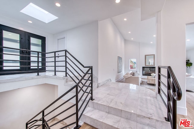 staircase featuring a skylight and high vaulted ceiling