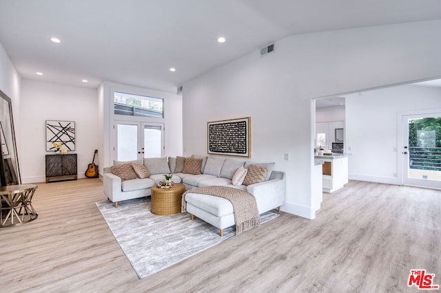 living room featuring french doors, vaulted ceiling, and light hardwood / wood-style flooring