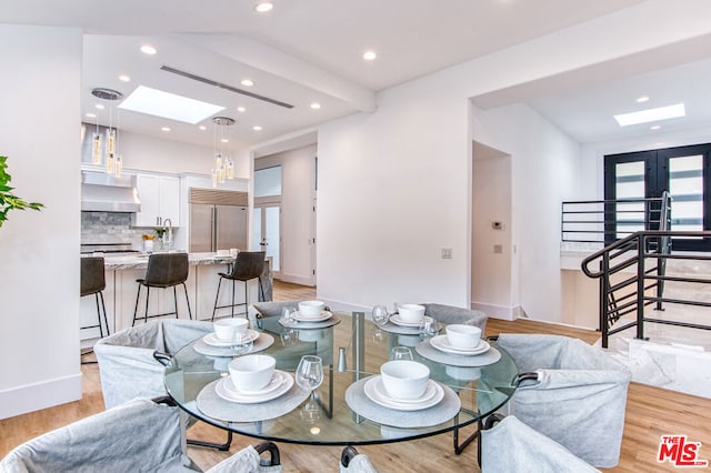 dining area featuring light wood-type flooring and a skylight