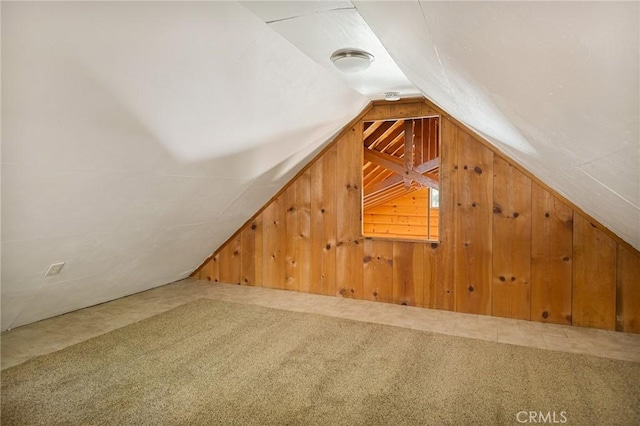 additional living space featuring vaulted ceiling, wooden walls, and carpet floors