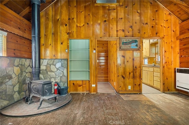 interior space featuring heating unit, high vaulted ceiling, wood walls, a wood stove, and hardwood / wood-style flooring