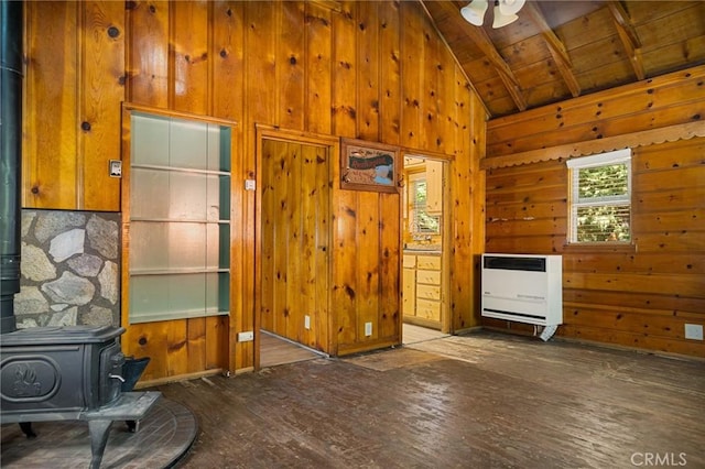 living room with heating unit, vaulted ceiling with beams, wooden walls, and a wood stove