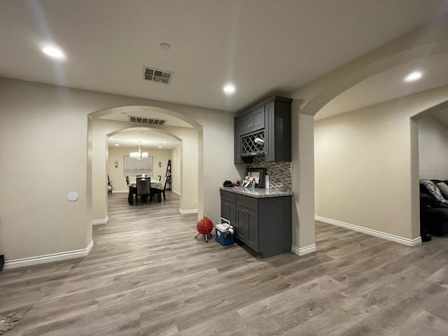 corridor featuring an inviting chandelier and hardwood / wood-style flooring