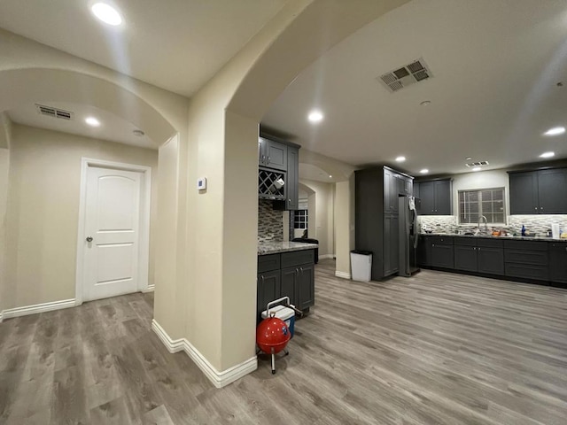 kitchen featuring tasteful backsplash, sink, light hardwood / wood-style flooring, and stainless steel refrigerator