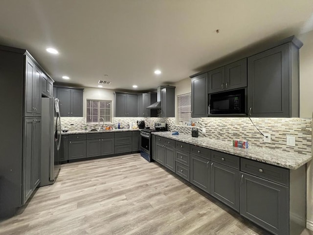 kitchen with stainless steel appliances, light stone countertops, and light hardwood / wood-style flooring