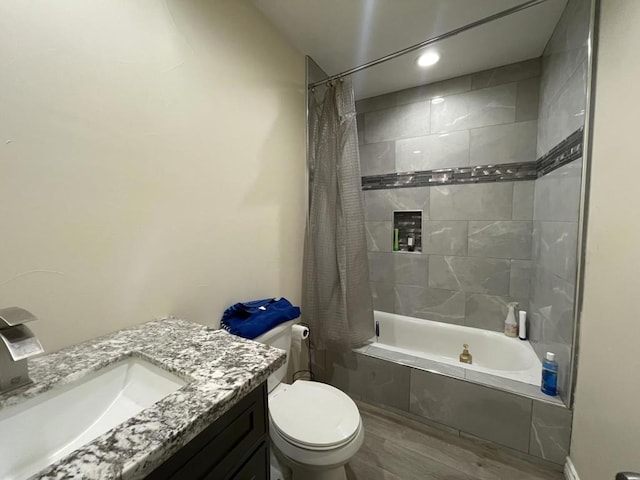 full bathroom with hardwood / wood-style flooring, vanity, shower / tub combo with curtain, and toilet