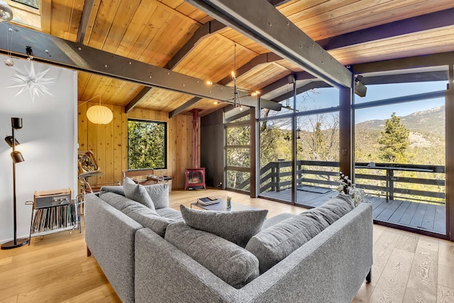 sunroom / solarium with wood ceiling, a mountain view, a wood stove, and vaulted ceiling with beams