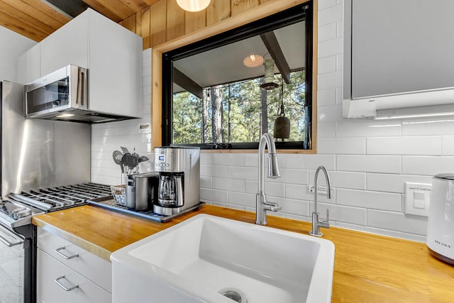 kitchen with tasteful backsplash, sink, stainless steel gas range oven, and white cabinets