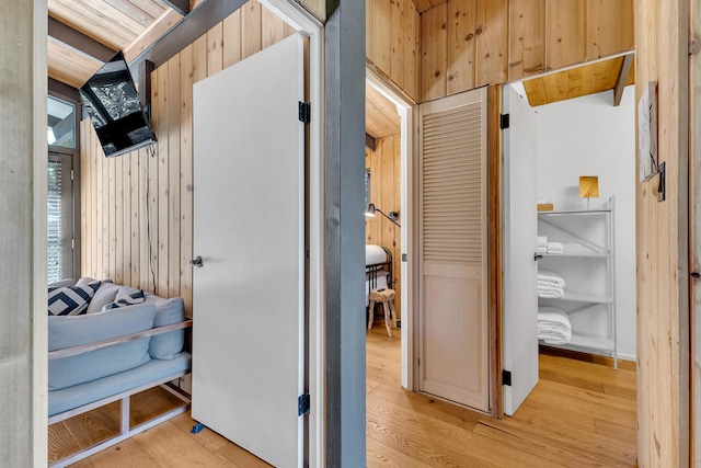 hallway featuring light hardwood / wood-style floors and wood walls