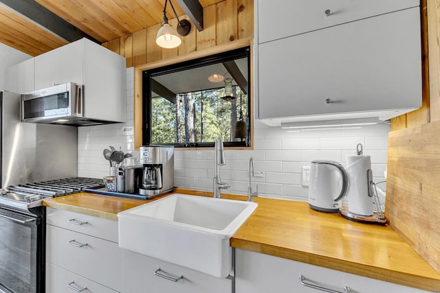 kitchen featuring sink, appliances with stainless steel finishes, tasteful backsplash, white cabinets, and wooden ceiling