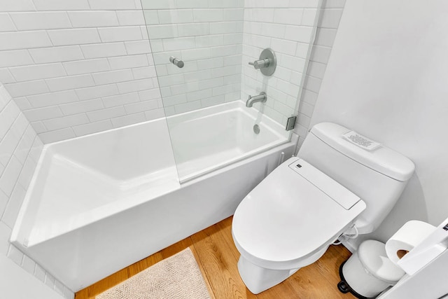 bathroom with tiled shower / bath combo, wood-type flooring, and toilet