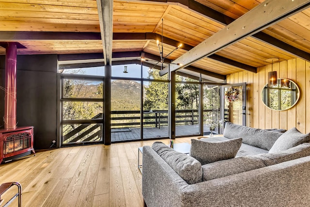 sunroom / solarium featuring lofted ceiling with beams, wooden ceiling, and a wood stove