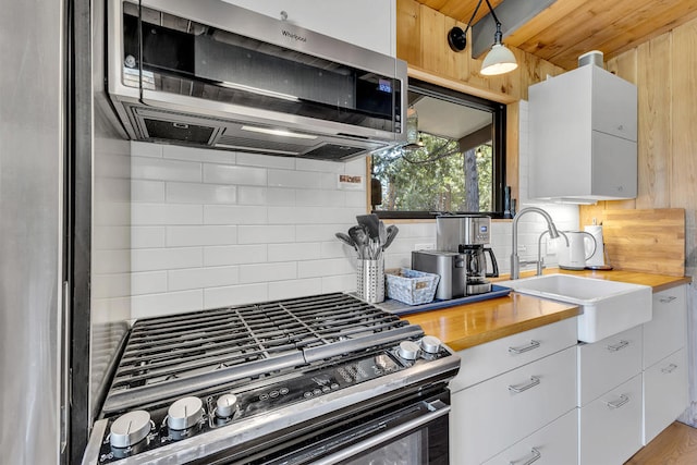 kitchen with stainless steel appliances, sink, decorative backsplash, and white cabinets