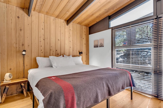 bedroom featuring hardwood / wood-style flooring, vaulted ceiling with beams, wooden ceiling, and wood walls