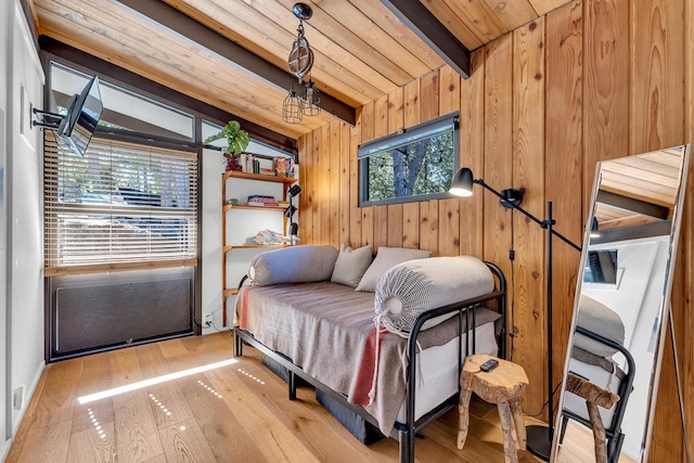 bedroom featuring beam ceiling, light wood-type flooring, wooden ceiling, and wood walls