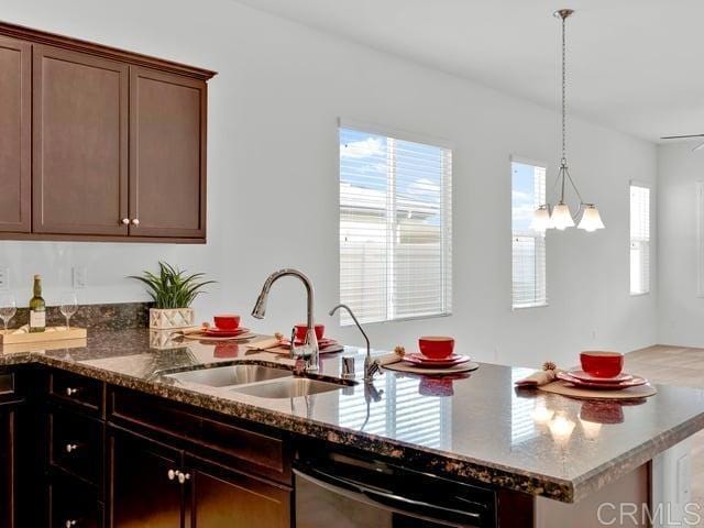 kitchen featuring pendant lighting, dishwasher, sink, dark stone counters, and dark brown cabinetry