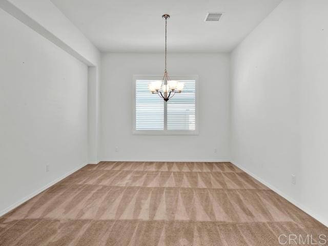 empty room featuring carpet flooring and a chandelier