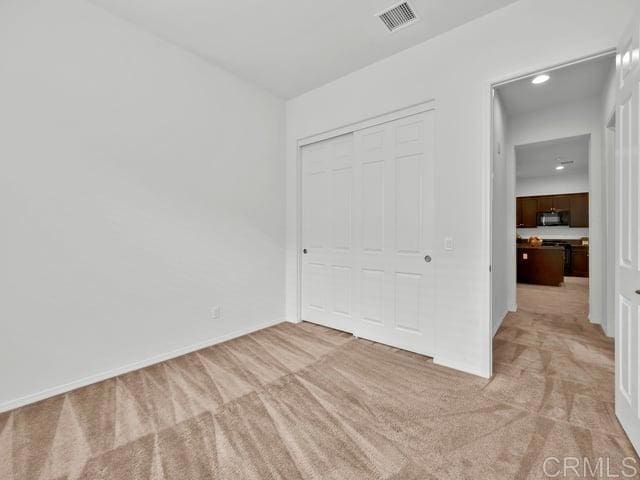 unfurnished bedroom featuring light carpet and a closet