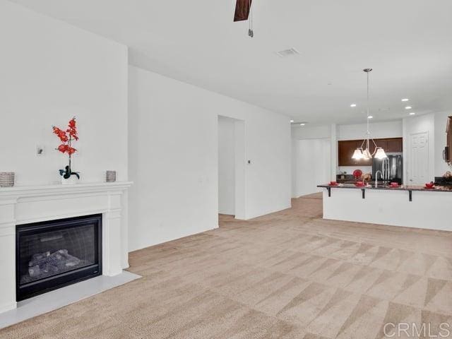 unfurnished living room featuring ceiling fan and light colored carpet