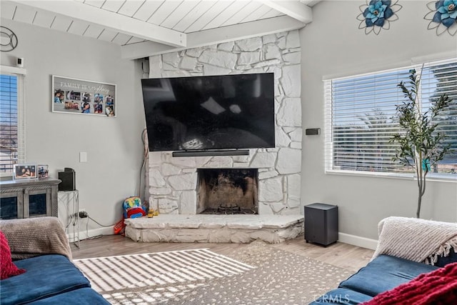 living room featuring beam ceiling, wood ceiling, a stone fireplace, and light hardwood / wood-style floors