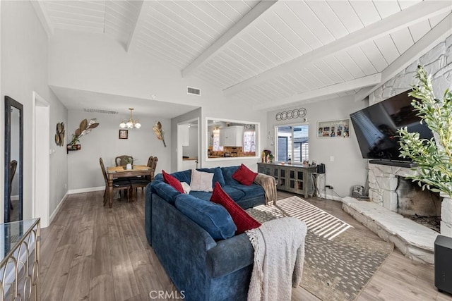 living room with an inviting chandelier, vaulted ceiling with beams, hardwood / wood-style flooring, and a fireplace