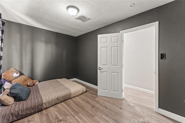 bedroom with a textured ceiling and light wood-type flooring