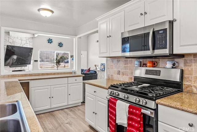 kitchen featuring sink, backsplash, white cabinets, and appliances with stainless steel finishes