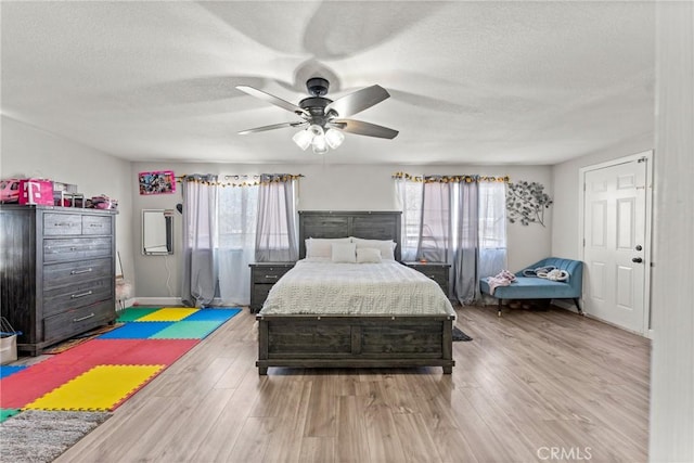 bedroom with multiple windows, ceiling fan, a textured ceiling, and light hardwood / wood-style floors