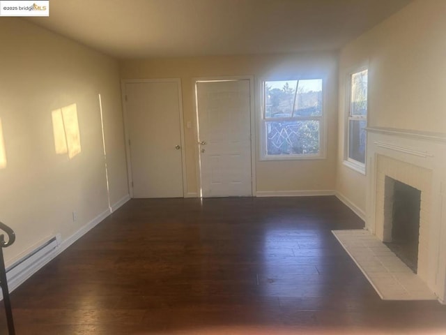 unfurnished living room with baseboard heating, dark hardwood / wood-style flooring, and a brick fireplace