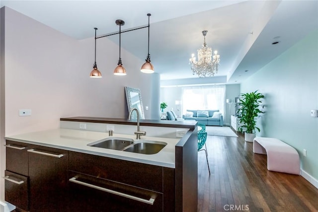 kitchen with sink, dark brown cabinets, dark hardwood / wood-style flooring, decorative light fixtures, and a chandelier