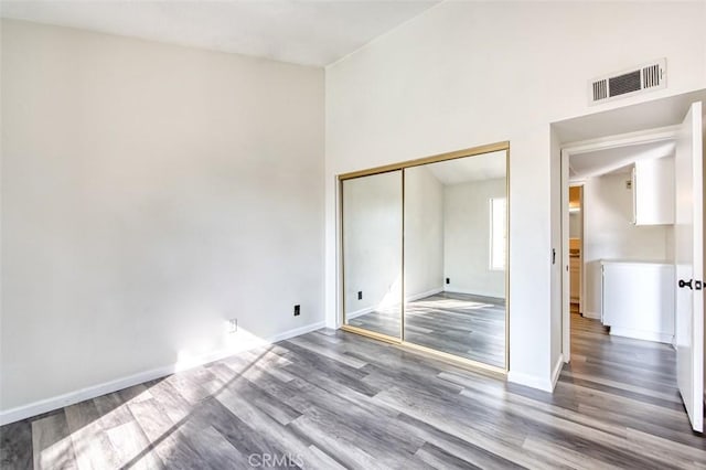 unfurnished bedroom featuring hardwood / wood-style floors, a closet, and a high ceiling