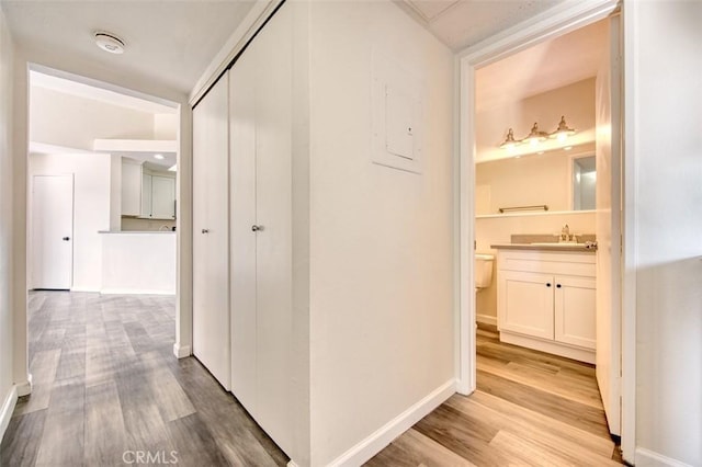 corridor with sink and light hardwood / wood-style flooring