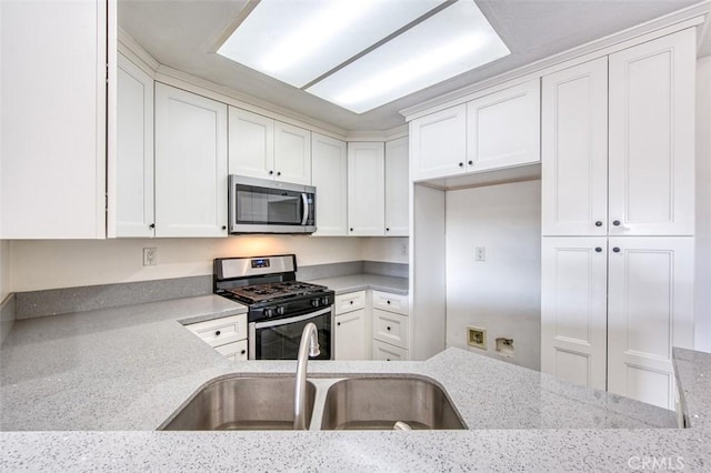 kitchen featuring appliances with stainless steel finishes, sink, white cabinets, and light stone counters