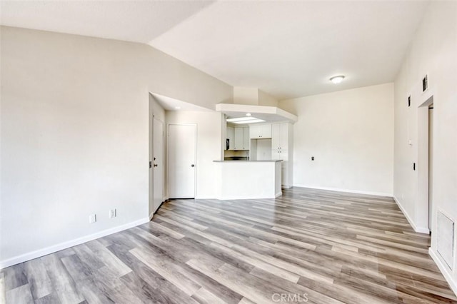 unfurnished living room featuring vaulted ceiling and light hardwood / wood-style floors