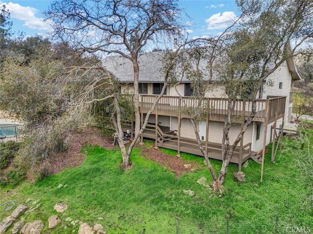 rear view of house with a wooden deck and a lawn