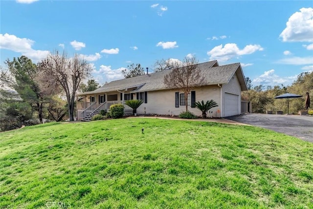 view of front of property featuring a garage, a front lawn, and covered porch