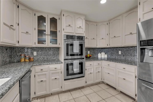 kitchen featuring white cabinetry, decorative backsplash, light tile patterned floors, light stone counters, and stainless steel appliances