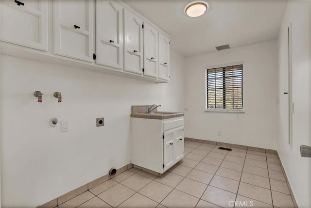 clothes washing area featuring cabinets, sink, light tile patterned floors, and electric dryer hookup