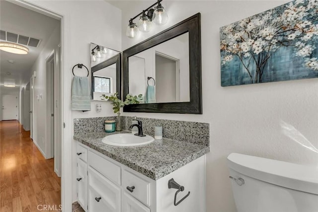 bathroom with vanity, toilet, and hardwood / wood-style floors